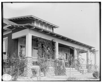 A woman on porch of Arts & Crafts home