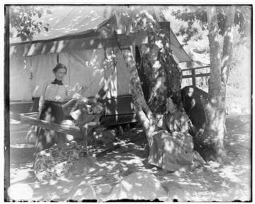 Two women and a young boy under the shade of a tree