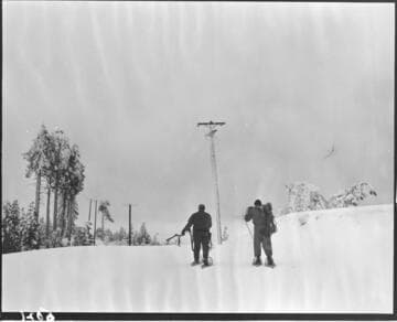 Linemen walking to distribution pole with snow shoes
