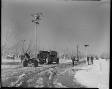 Linemen working on pole in snow at corner of Ave. K