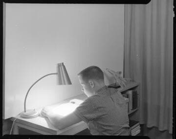 Young student reading and studying at his desk with different lighting