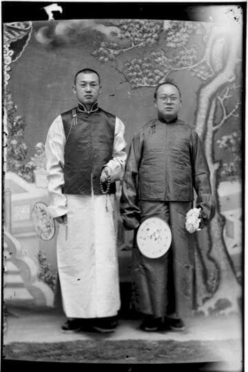 Portrait of two Chinese men standing, both wearing glasses