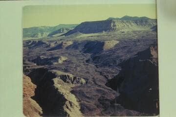 Whitmore Wash at lower left.  Upper left is Mt. Trumbull, upper left center is Mt. Logan.  The bosomy peaks of Mt. Emma are upper right.  The road to the rim can be seen on the lava flow
