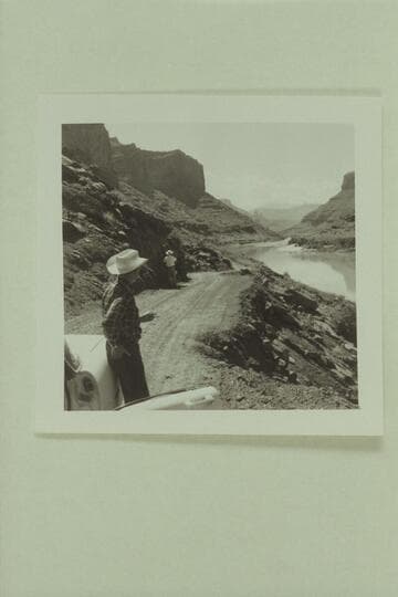 Down the Colorado River toward Castle Valley.  The Fisher Towers in distance.  George White stands by the car while Russ Haverick takes photos of the possible location for a Powell picture scene