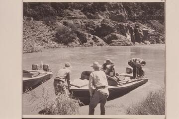 Shoving off from right bank above Bright Angel Creek.  The bridge is upper right.  Hugh Cutler shoves off while Joe Desloge watches the job.  Ballard Atherton is at the controls and Bill Beer at the moorings