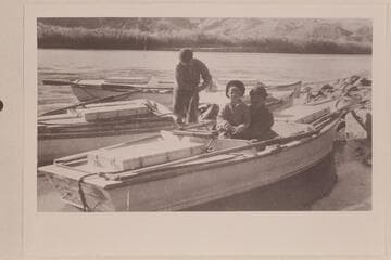 Virginia Lowrey sits in Owen Clark's lap.  Val Woodbury coils a line.  Lees Ferry.  Pathe-Bray Expedition.  Copy of print in David C. Lowrey collection