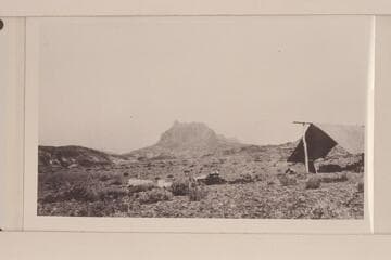 Looking northeast up San Juan Canyon from point between mouths of Clay Gulch and Copper Canyon.  Camp is on gravel terrace.  Mesa is capped by Navajo, Todilto, and Wingate formations.  Irregular hills are in areas of Chinle formation