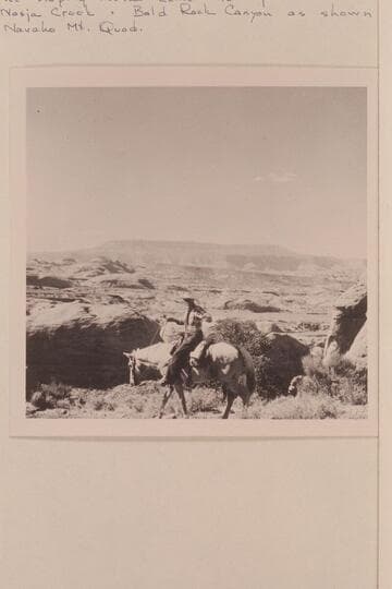 Masland on the trail between Bald Rock Creek and Nasja Creek.  Fifty Mile Mountain forms the skyline.  The sloping mesa center to right is 4903 between Nasja Creek and Bald Rock Canyon as shown on Navajo Mountain Quad