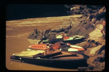 [three motorboats tied up at riverbank]