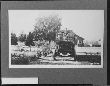 A man sitting in the front seat of an ALCO truck on a suburban street
