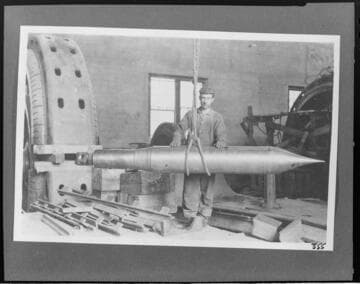 A man standing behind the needle for the prime mover waterwheel at Kern River #1 Hydro Plant