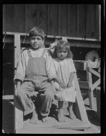 Native American boy and girl sitting on steps of house