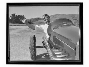 Race car driver Barney Oldfield waving from car at Legion Ascot Speedway, Los Angeles