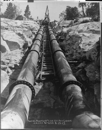 This dramatic view shows the penstock being laid up the 80 percent grade above Powerhouse #1 during August of 1913