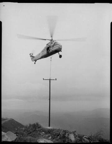 Large Sikorsky helicopter airlifting and placing pre-assembled poles into remote sites in Santa Barbara