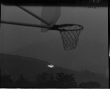 Illuminated "M" (Monrovia) on hillside with basketball hoop in foreground