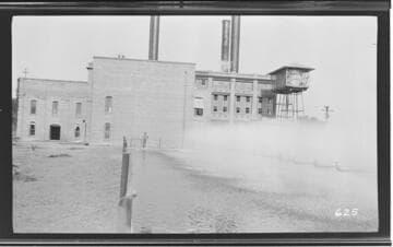 An operator standing outside of the Visalia Steam Plant by the cooling pond