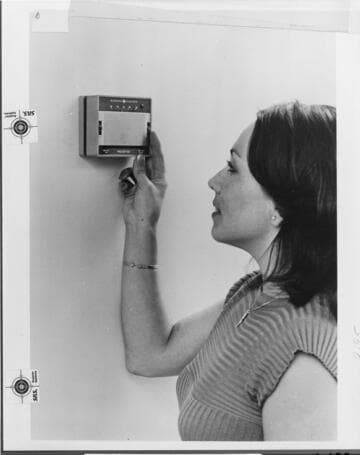 A woman adjusting the thermostat in her home