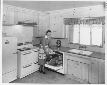 A housewife posed in her home next to the electric dishwasher