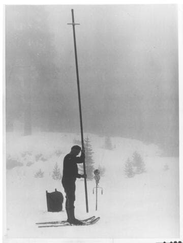 An Edison snow surveyor prepares to force a hollow tube into the snow
