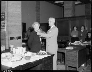 Man pinning corsage on lady in office