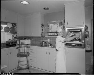 Chef in kitchen taking food out of oven