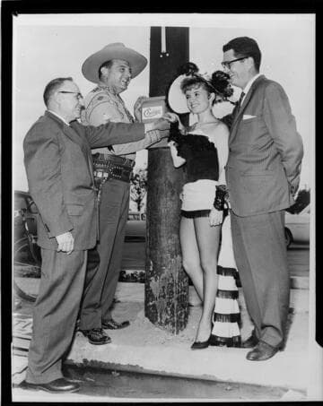 Two men in suits, a cowboy and a dance hall girl switching on the power