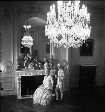 Costumed couple in front of fireplace in the large drawing room in the Huntington residence