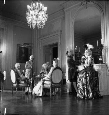 Six people in period costume in the small drawing room in the Huntington residence